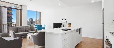 A modern apartment with a kitchen island, a grey sofa, and a city view.