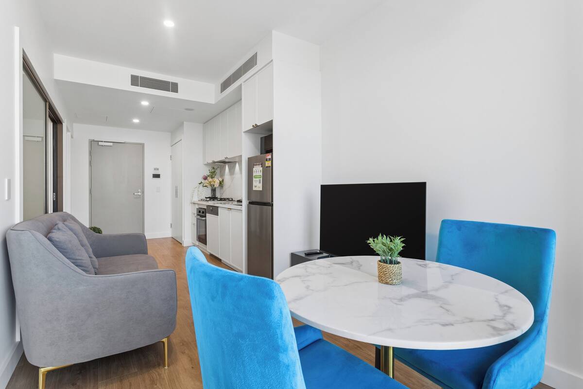 A modern kitchen with white cabinets, a stainless steel refrigerator, and a built-in oven.