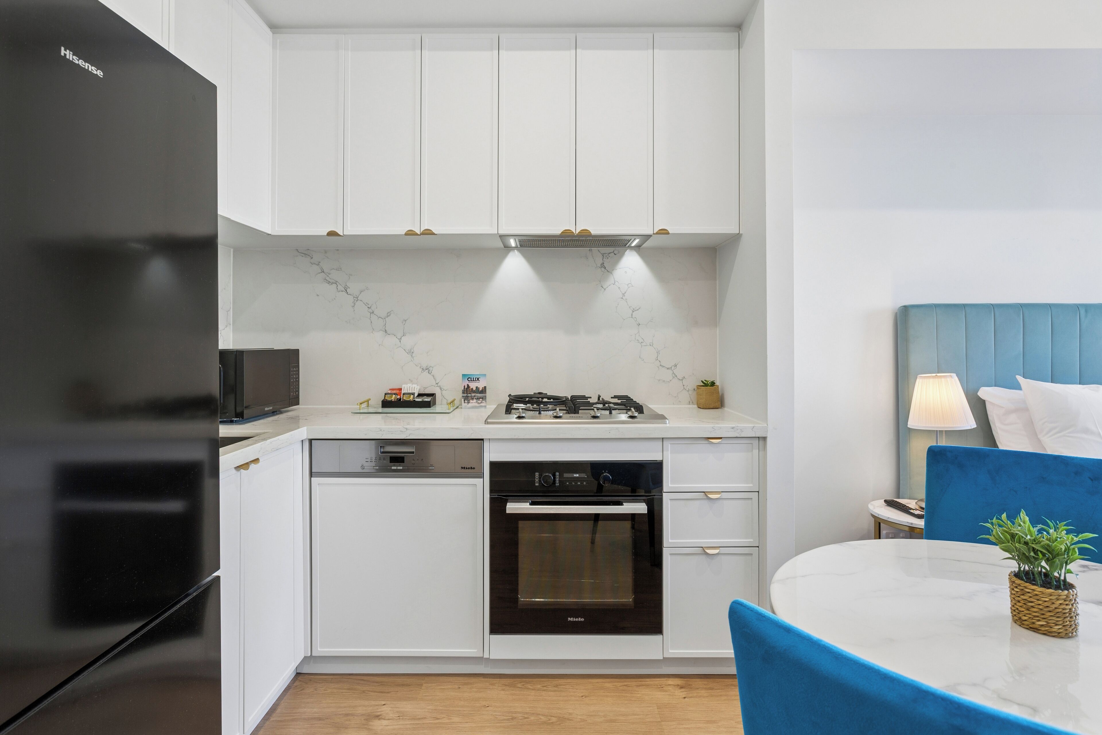 A modern kitchen with white cabinets, a black refrigerator, a built-in oven, and a gas stove.
