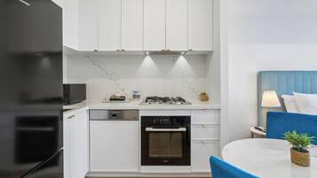 A modern kitchen with white cabinets, a black refrigerator, a built-in oven, and a gas stove.