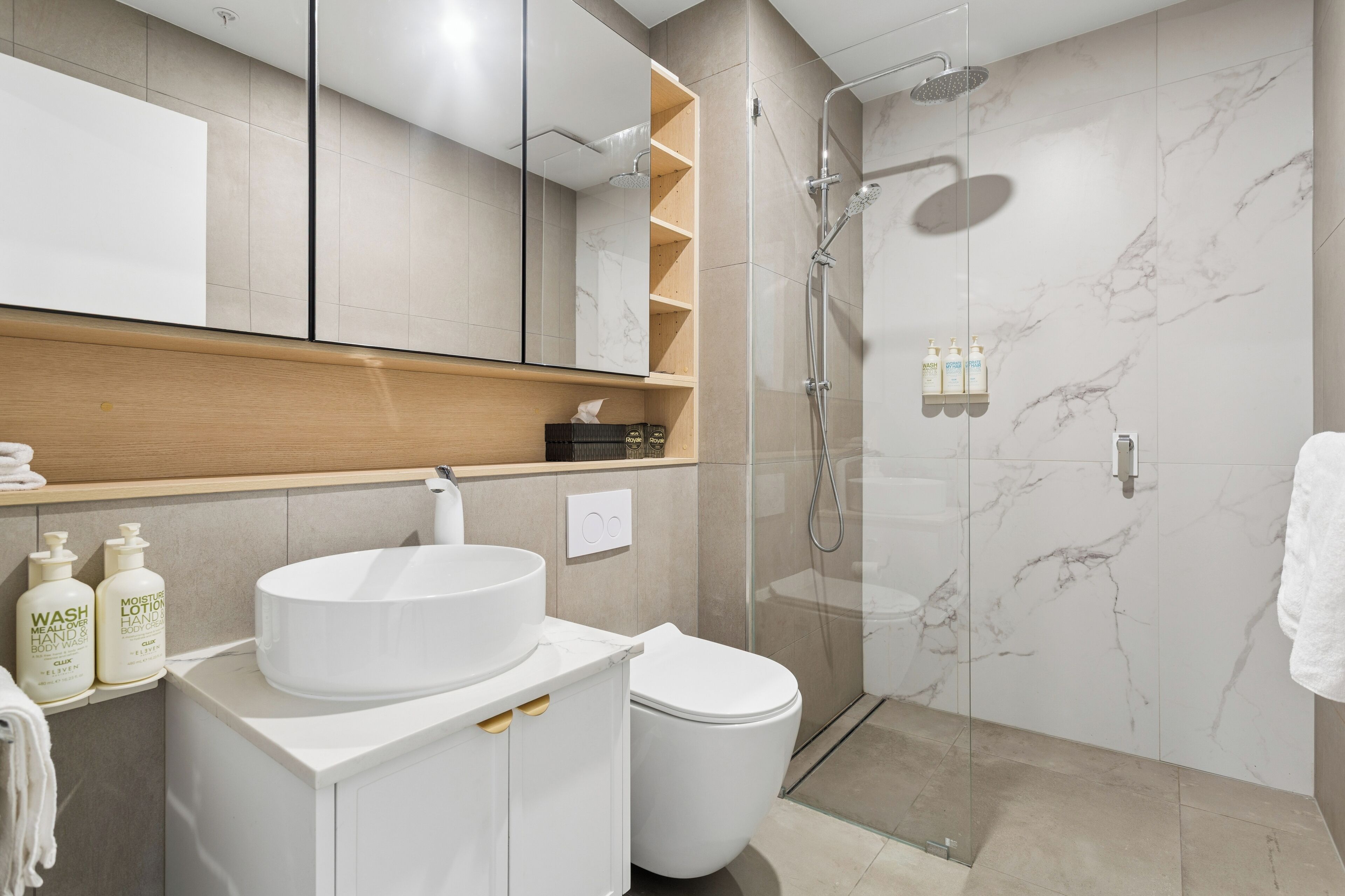 A modern bathroom with a glass-enclosed shower, a white sink, and a toilet.
