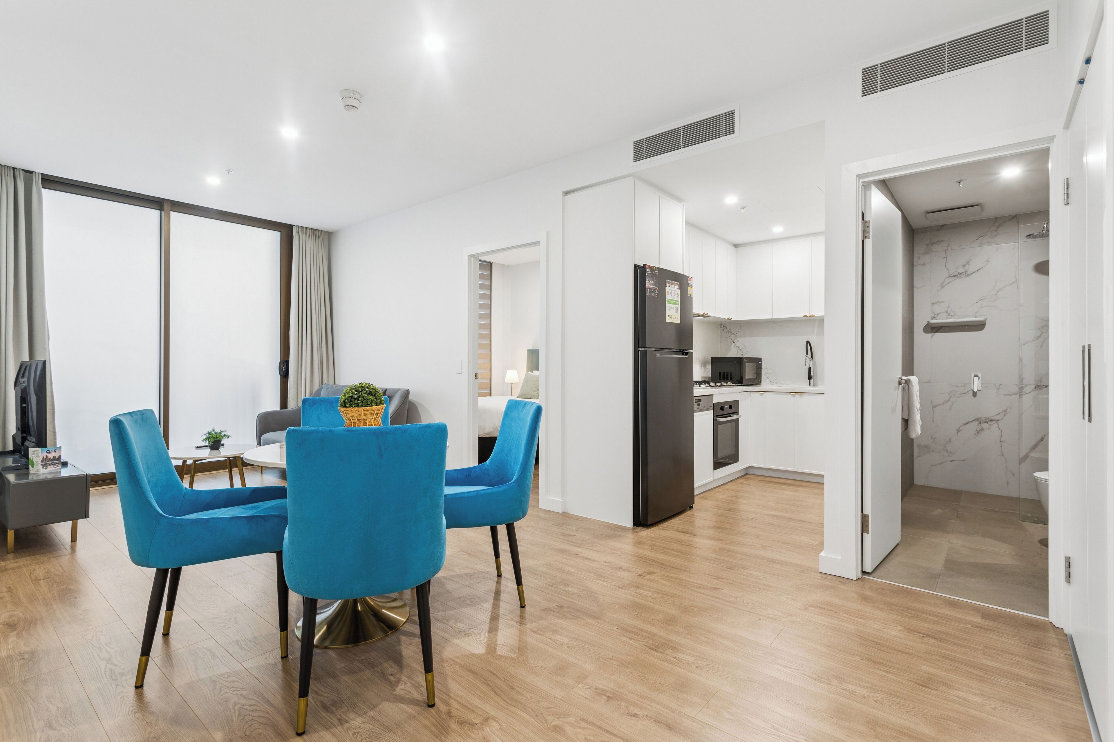 A modern apartment with a dining area, kitchen, and bathroom.