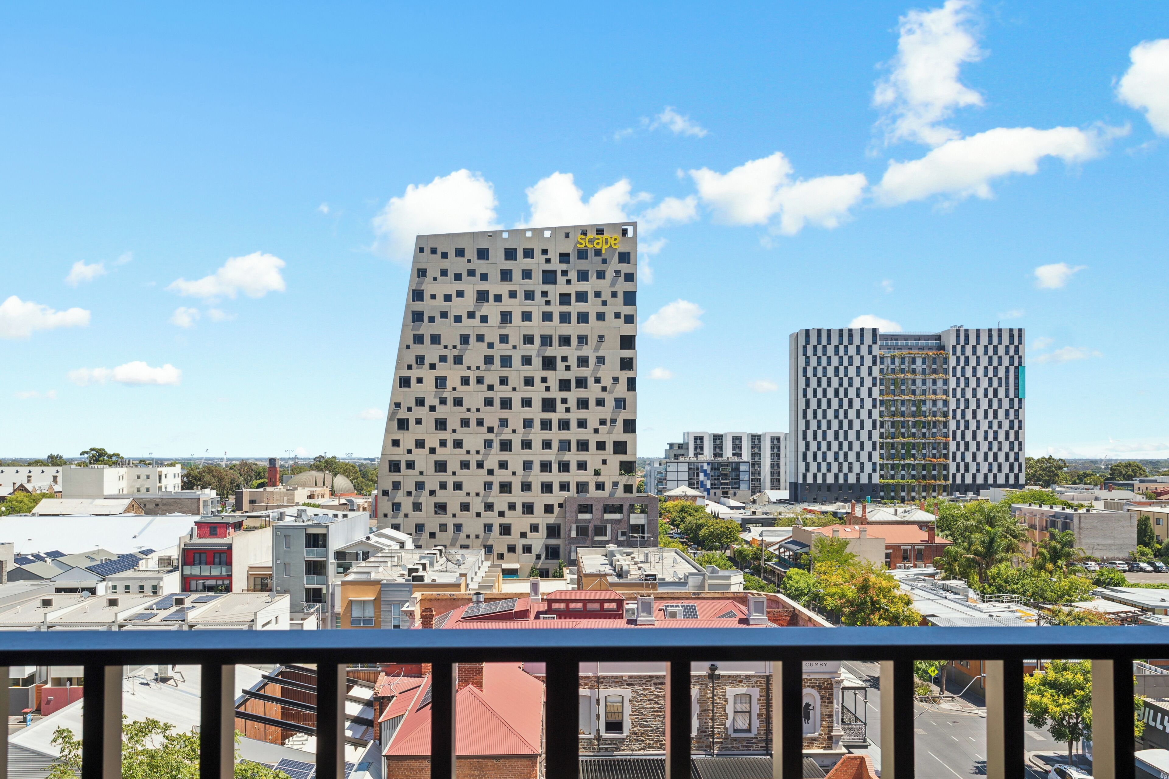 Stadsgezicht met moderne gebouwen, waaronder een opvallende wolkenkrabber met een rastergevel en een andere met een ruitpatroon.