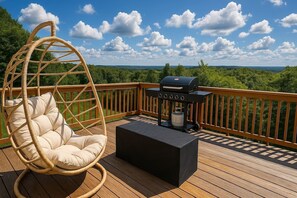 Eine Terrasse mit Hängesessel, Grill und Tisch.