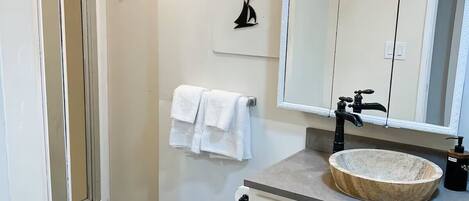 Un baño con inodoro blanco, lavabo de mármol, espejo y un perchero para toallas.