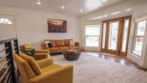 A modern living room with a brown leather sofa, yellow armchairs, and a coffee table. - Entire House Between Zion & Bryce w/ Hot Tub! (Orderville)
