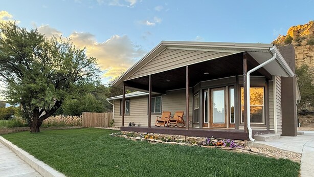 A modern house with a covered porch, a stone pathway, and a well-maintained lawn. - Entire House Between Zion & Bryce w/ Hot Tub! (Orderville)
