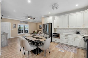 A modern kitchen with white cabinets, stainless steel appliances, and a dining area with a table and chairs.