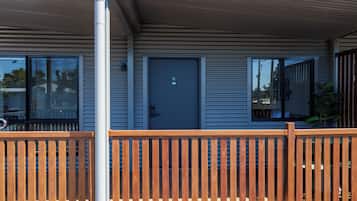 A modern building with a blue door, a wooden fence, and a metal roof.