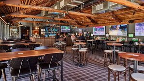 Ein Restaurant mit Holzbalken, mehreren Bildschirmen und einem Schachbrettmuster-Boden.