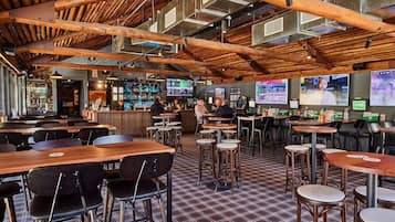 Un restaurant avec des poutres en bois, plusieurs écrans et un sol à carreaux.