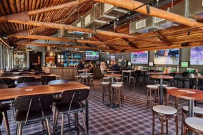 A restaurant with wooden beams, multiple screens, and a checkered floor. - Coomera Lodge Hotel (Oxenford)