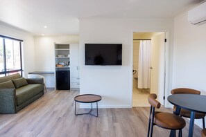 Uma sala de estar moderna com um sofá, uma mesinha e uma TV fixada na parede.