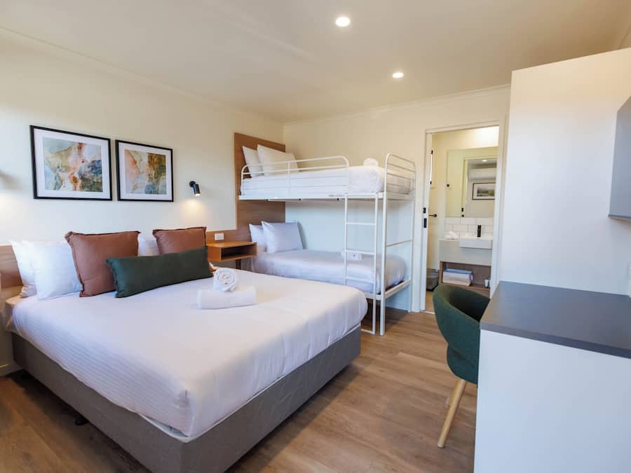 Une chambre d’hôtel équipée d’un lit superposé, d’un bureau, d’une chaise et d’une petite kitchenette.