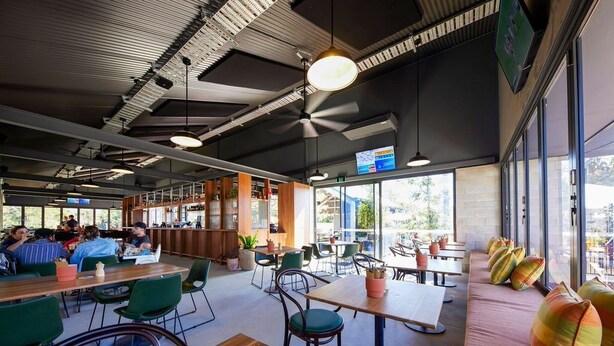 A modern cafe with indoor seating, large windows, and a bar area. - Coomera Lodge Hotel (Oxenford)