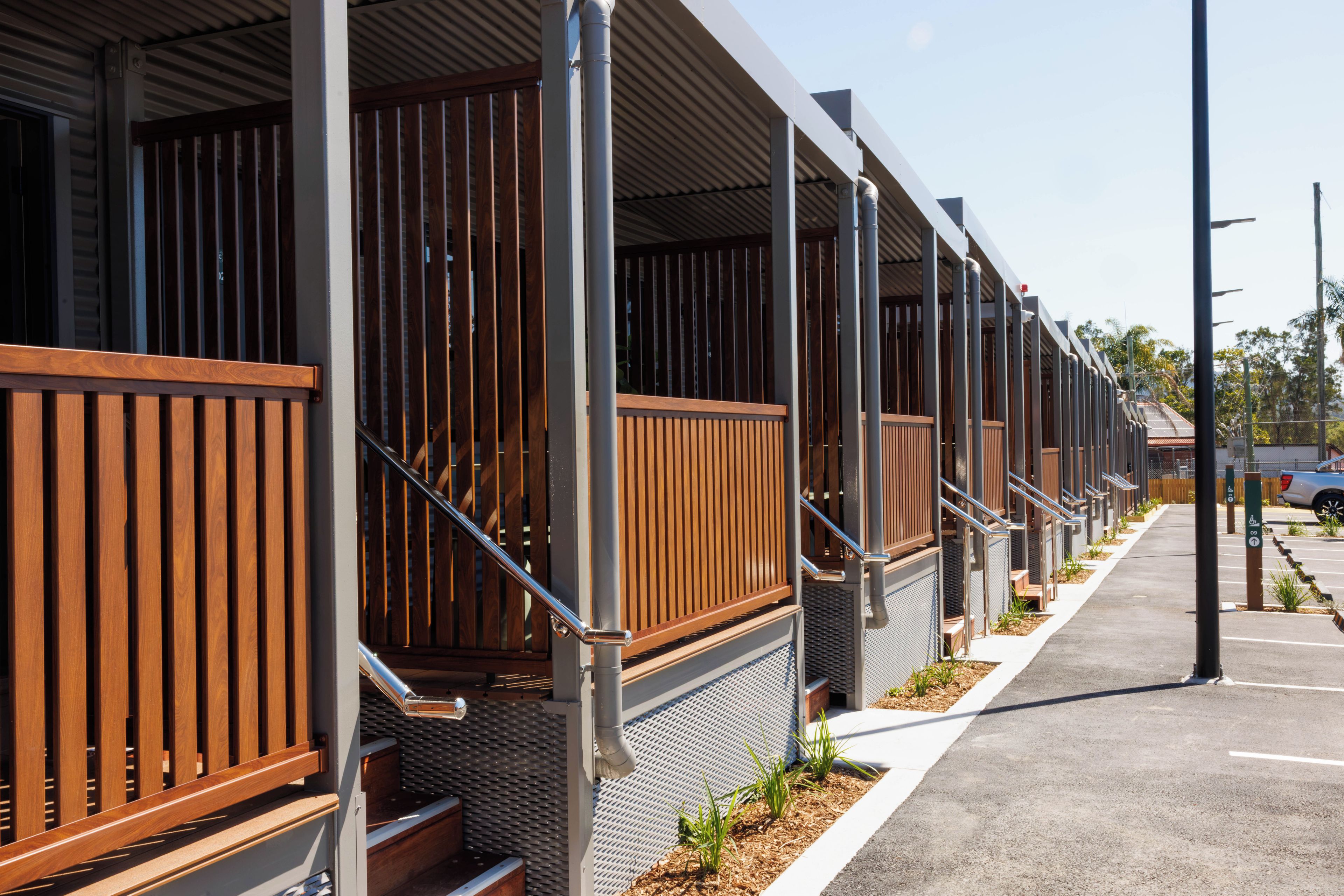 A row of hotel rooms with wooden railings and metal staircases.