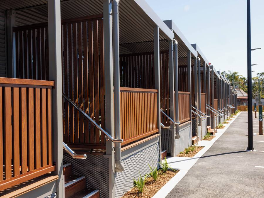 Una hilera de habitaciones de hotel con barandillas de madera y escaleras de metal.