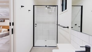 A modern bathroom with a glass-enclosed shower, a white sink, and a mirror. - Coomera Lodge Hotel (Oxenford)