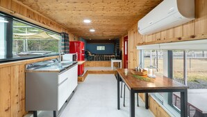 Une cuisine de taille réduite avec des murs en bois, un réfrigérateur rouge, un four à micro-ondes et un évier.