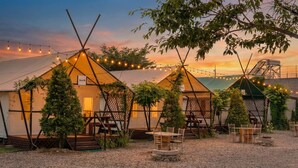 Une série de yourtes décorées de guirlandes lumineuses, meublées de mobilier en bois et dotées d’un sol en gravier.