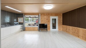 Une cuisine moderne équipée d’un four à micro-ondes, un coin repas avec une table et des chaises, un téléviseur et une grande fenêtre donnant sur un terrain de jeux.
