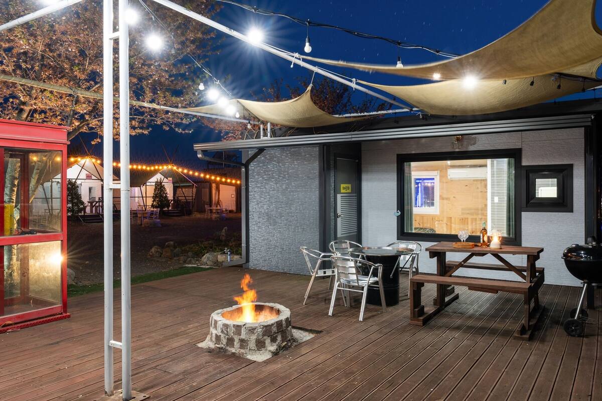 A wooden deck with a fire pit, outdoor seating, and a red booth.
