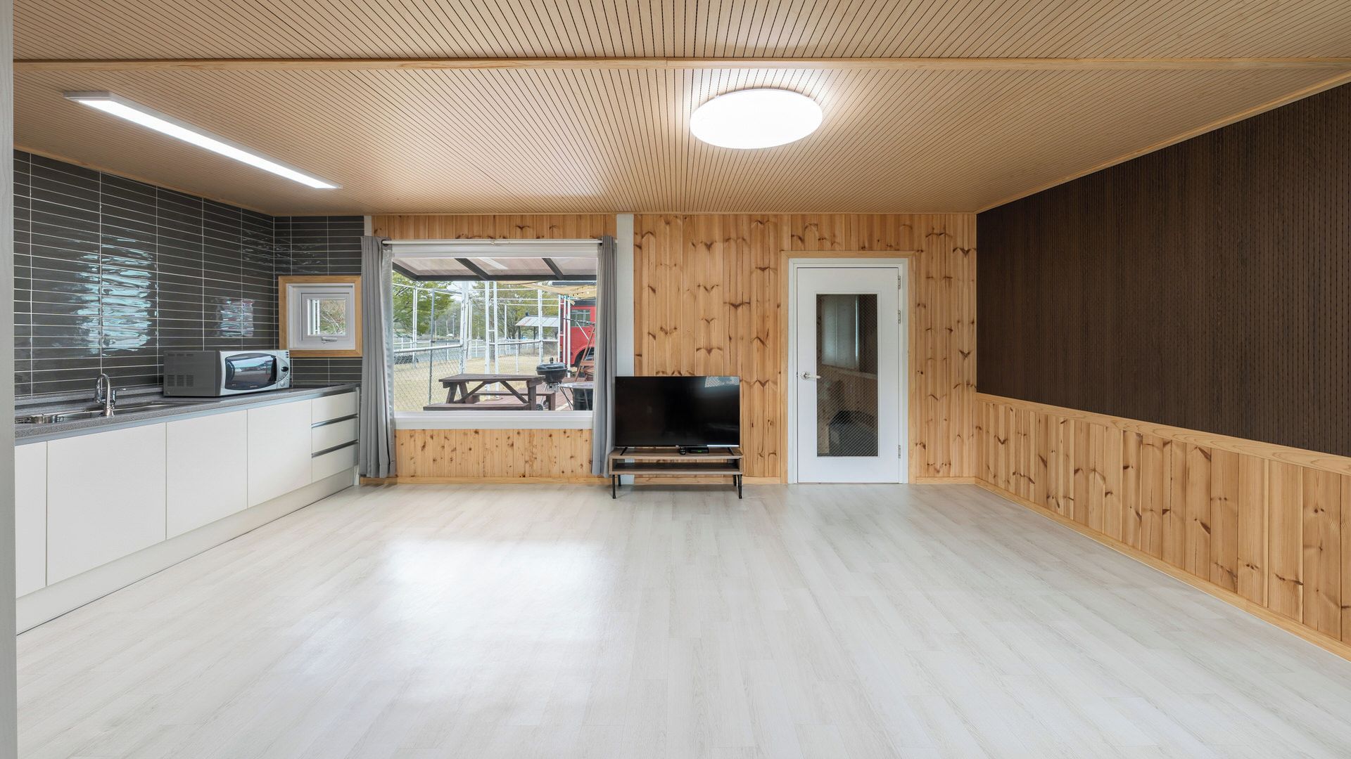 A modern kitchen with a microwave, a sink, and a window overlooking a patio area.