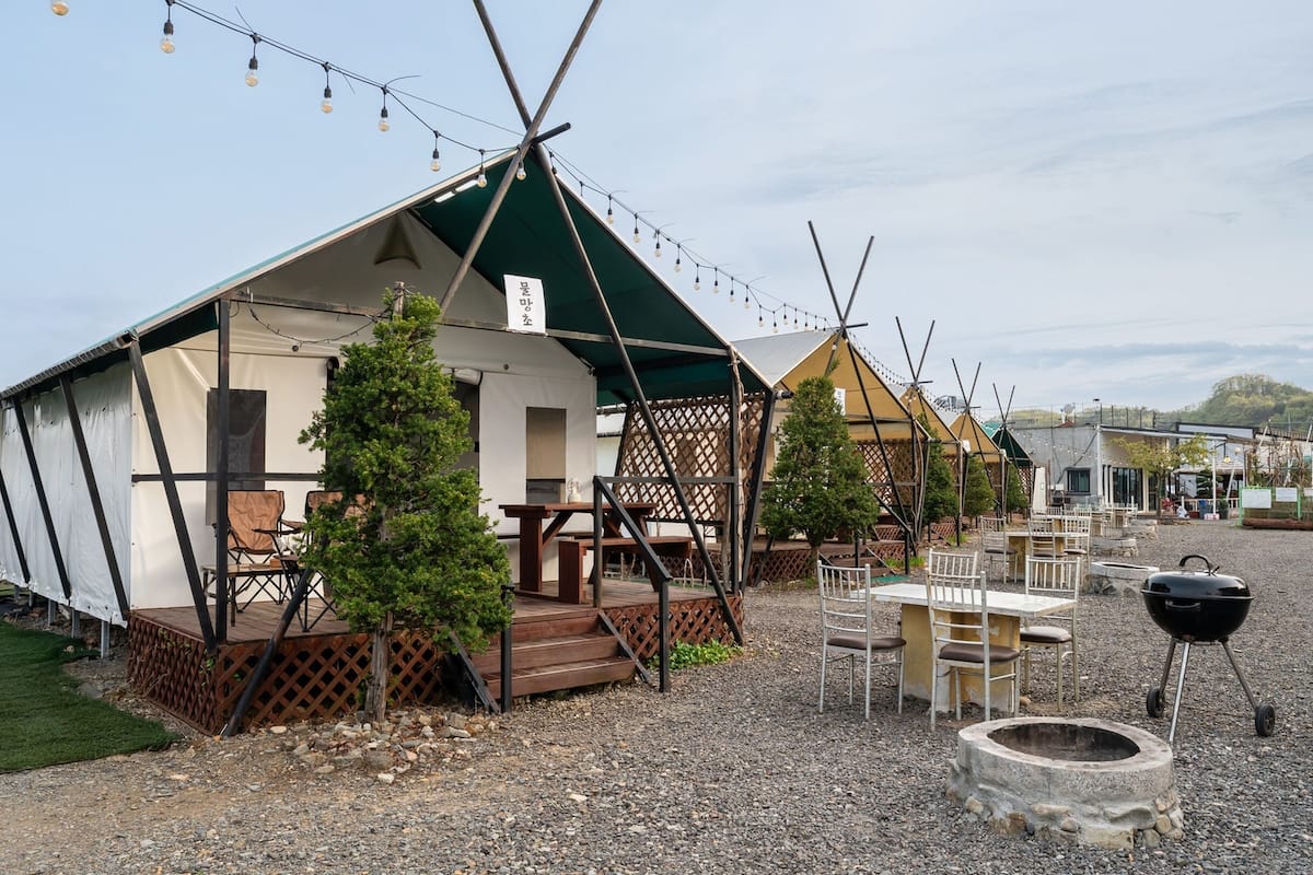 A rustic cabin-style accommodation with a green roof, outdoor seating, and a barbecue area.