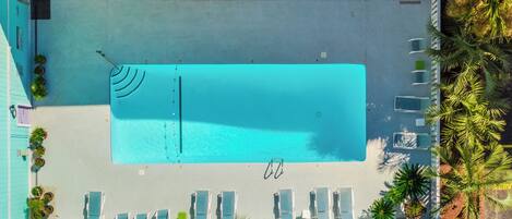 Vista aérea de una zona de piscina con sillones reclinables y una alberca.