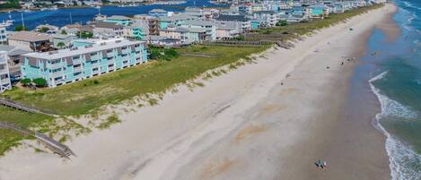 A coastal hotel with multiple-story buildings, a sandy beach, and a view of the ocean.