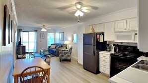 A compact living space with a dining area, kitchen, and a sofa in the living room. - A Place At The Beach #1D by Carolina Retreats (Carolina Beach)