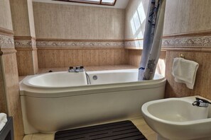 A bathroom with a bathtub, a bidet, and a shower curtain.