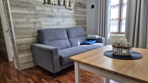 A living room with a grey sofa, a wooden table, and a decorative item on the table. - 1a152 Apartamentos el Veleru Popa (Gijón)