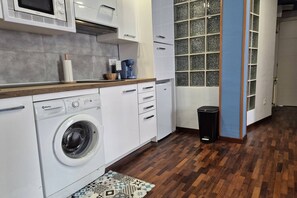 A compact kitchen with a washing machine, a microwave, and a coffee maker on the countertop.