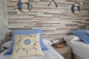 A bedroom with a wooden plank wall, two beds with matching pillows, and two life rings on the wall.