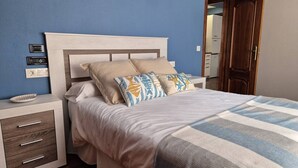 A bedroom with a bed, nightstands, a dresser, and a door. - 1a152 Apartamentos el Veleru Popa (Gijón)