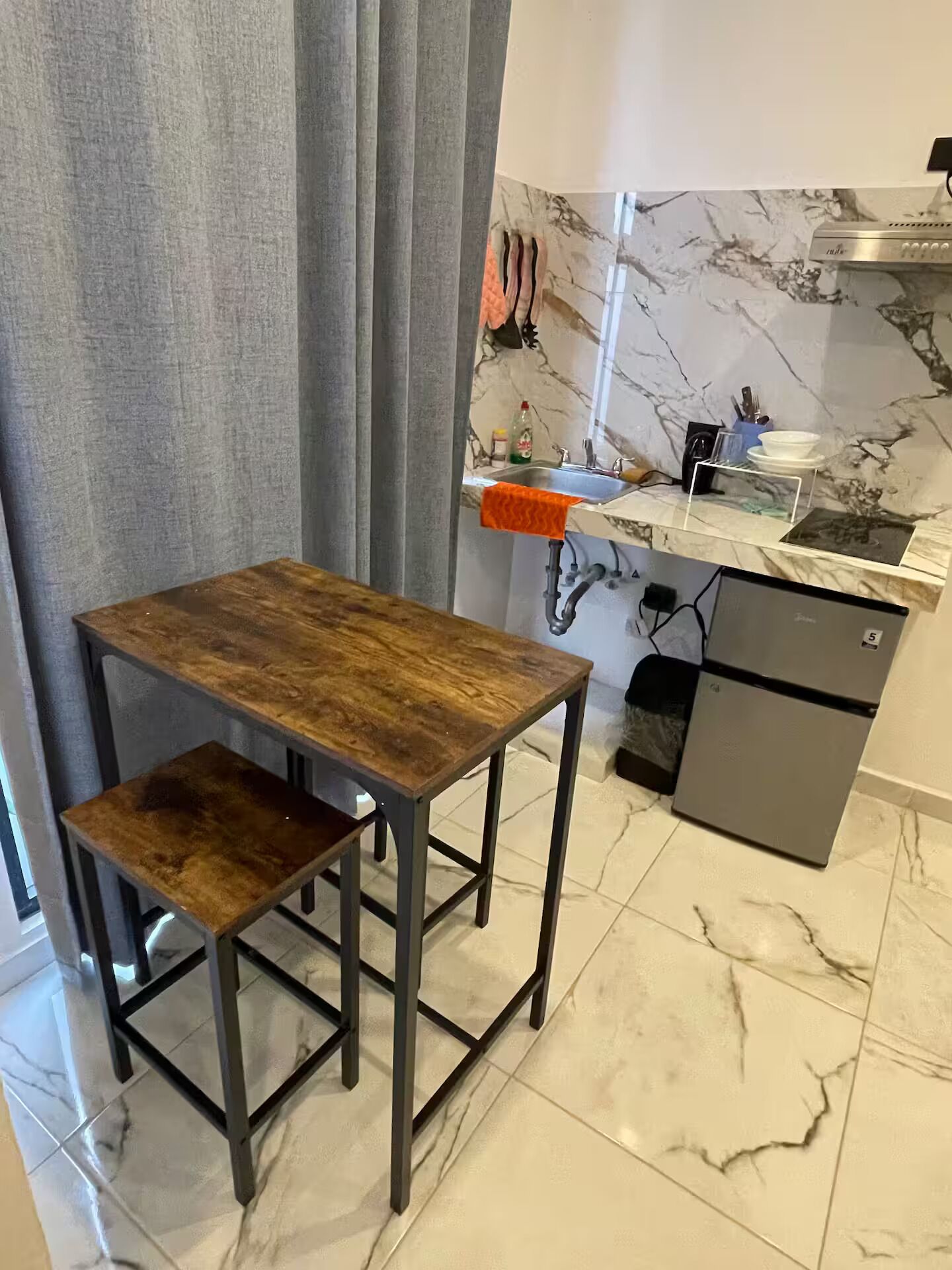 A compact kitchen with a marble countertop, a built-in oven, and a small sink.