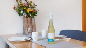 A dining table with a bottle of wine, plates, and a vase of flowers. - Lake Constance Bungalow – 'Souterrain' Apartment with Private Terrace, Shared Garden & Wi-Fi (Immenstaad am Bodensee)
