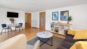 A modern living room with a sofa, coffee table, and a bookshelf. - Lake Constance Bungalow – 'Souterrain' Apartment with Private Terrace, Shared Garden & Wi-Fi (Immenstaad am Bodensee)