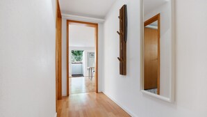 A hallway with wooden flooring, white walls, and a wooden door leading to another room. - Lake Constance Bungalow – 'Souterrain' Apartment with Private Terrace, Shared Garden & Wi-Fi (Immenstaad am Bodensee)