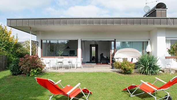 A modern house with a patio, two sun loungers, and a dining area. - Lake Constance Bungalow – 'Souterrain' Apartment with Private Terrace, Shared Garden & Wi-Fi (Immenstaad am Bodensee)