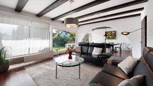 Un salon moderne avec une table basse en verre, un canapé en cuir et un coin repas comprenant une table et des chaises.