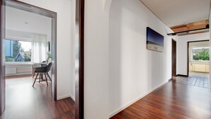 Un intérieur moderne avec un plancher en bois, des murs blancs et un coin repas comprenant des chaises et une table.