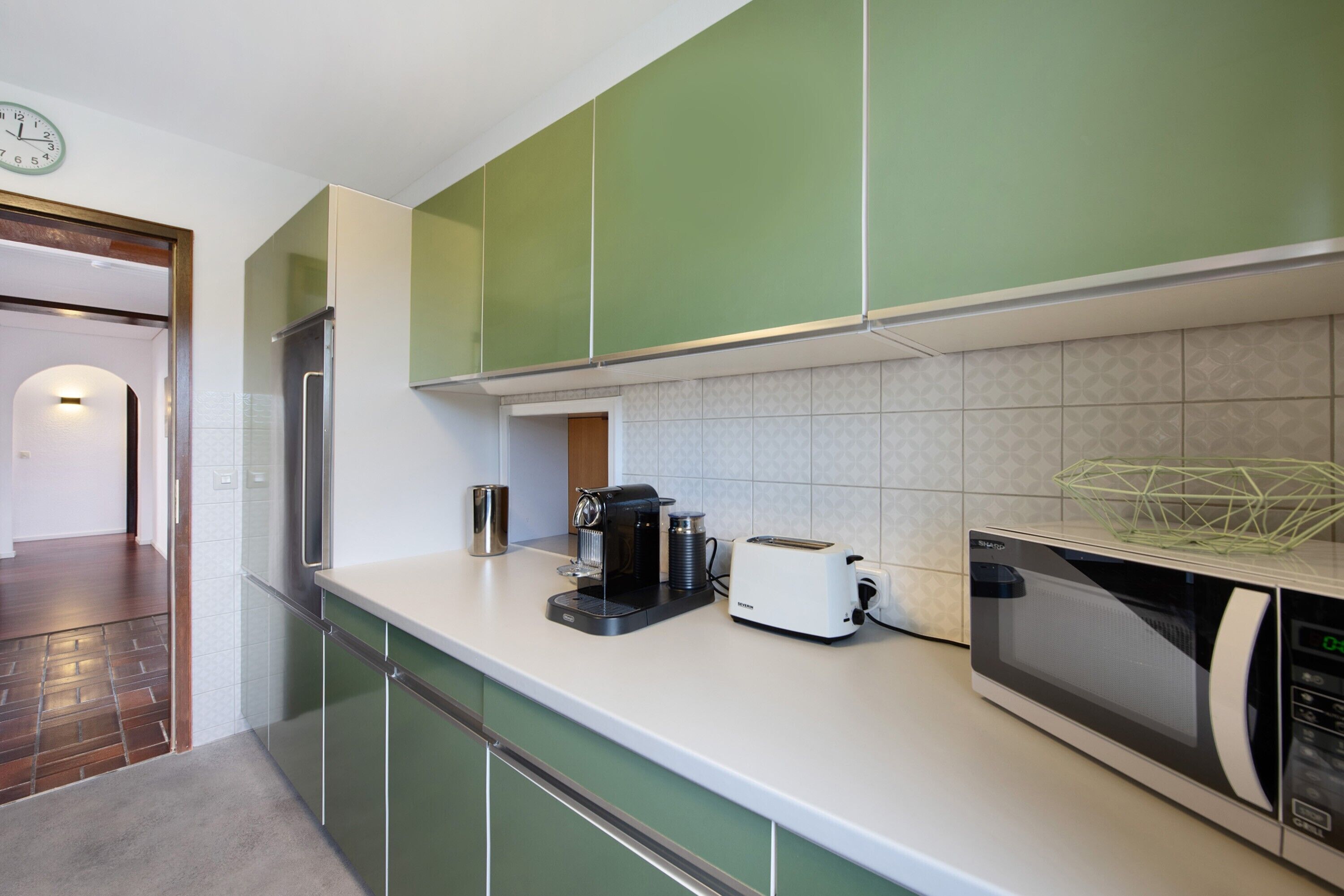 A kitchen with green cabinets, a microwave, a toaster, and a coffee maker.