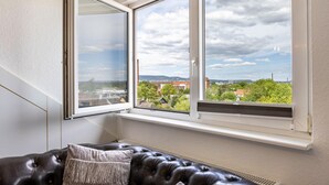 A room with a large window, a black leather sofa, and a radiator. - Grimms Suite Apartment (Kassel)