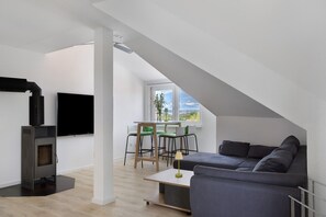 Una sala de estar moderna con chimenea, un sofá, un comedor con sillas y un televisor.