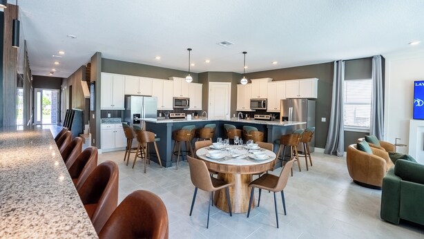 A modern kitchen with white cabinets, a central island, and a dining area with a round table and chairs. - Luxury Golf Estate with Simulator, Bowling, Sauna (Reunion)