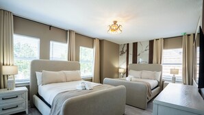 A hotel room with two beds, a desk, and a ceiling light. - Luxury Golf Estate with Simulator, Bowling, Sauna (Reunion)