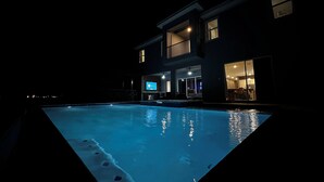 A two-story house with a swimming pool at night. - Luxury Golf Estate with Simulator, Bowling, Sauna (Reunion)