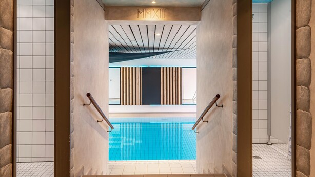 A swimming pool with a view of the sky, a ceiling with a Roman numeral sign, and a tiled floor.